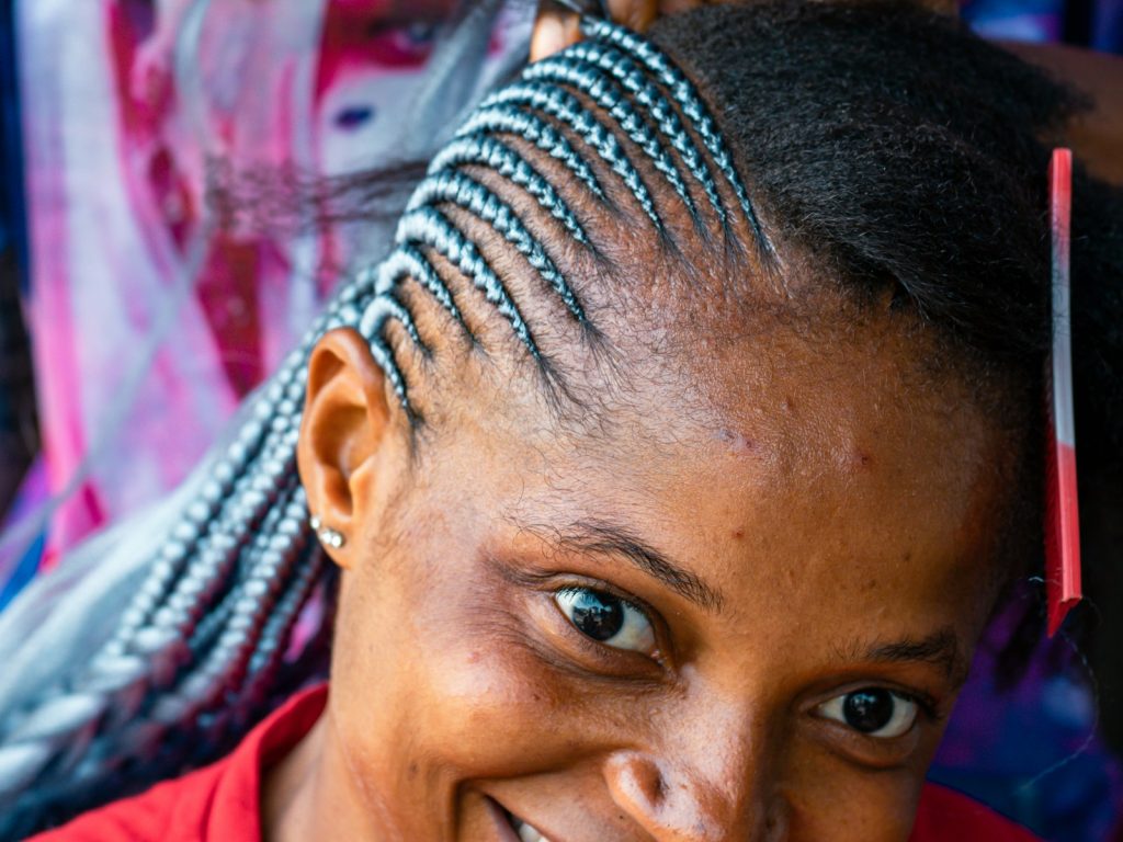Close-up of a braider sectioning hair during a knotless braids appointment in San Diego